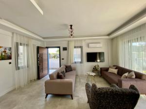 a living room with two couches and a tv at House of ALICE - Villa with Pool near Çalış Beach in Fethiye
