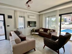 a living room with a couch and chairs and a tv at House of ALICE - Villa with Pool near Çalış Beach in Fethiye