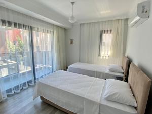 a hotel room with two beds and a window at House of ALICE - Villa with Pool near Çalış Beach in Fethiye +9 photos