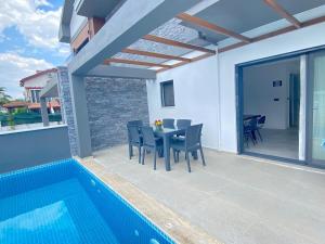 a patio with a table and chairs next to a swimming pool at House of ALICE - Villa with Pool near Çalış Beach in Fethiye