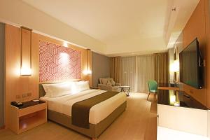 a hotel room with a bed and a television at Luxu Hotel and Resort in Panglao Island