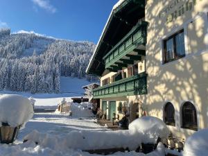 a building covered in snow next to a mountain at Mühlradl Apartments Gosau in Gosau