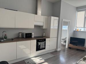 a kitchen with white cabinets and a microwave at Chris cosy retreat in Buckinghamshire