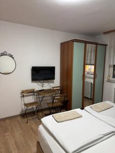 two beds in a room with a tv and a desk at Sobe Zimmer Frei in Požega