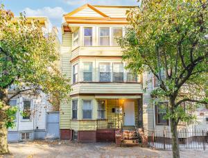 a large yellow house with a tree in front of it at Chic 2BR Apartment Near Branch Brook Park in Newark