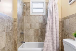 a bathroom with a tub and a shower curtain at Chic 2BR Apartment Near Branch Brook Park in Newark +23 photos