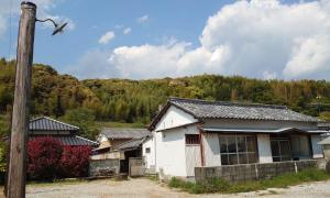 un grupo de casas con una montaña en el fondo en コワーキングスペース kuzume Base ゲストハウス 古朴-MOKU-1棟貸の宿, en Konan