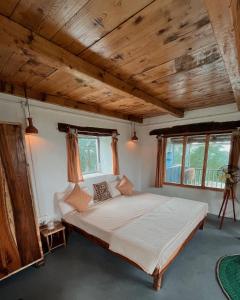 a bedroom with a large bed with wooden ceilings and windows at The Attic Library by AVVAs Stays in Bīr