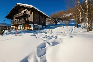 a snow covered house with footprints in the snow at Chalet familiale spacieux - près de Villars in Huémoz +44 photos