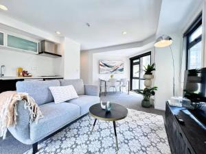 Una sala de estar con un sofá azul y una mesa. en Prime CBD Location- Walk to Spark Area & Queen St, en Auckland