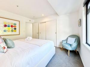 Un dormitorio con una cama y una silla azul. en Prime CBD Location- Walk to Spark Area & Queen St, en Auckland