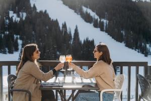 Dos mujeres sentadas a una mesa sosteniendo vasos en Totem, Friendly Hotel & Spa, en Flaine