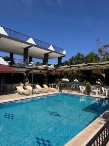 a swimming pool with chairs and umbrellas at a hotel at BEGONYA HOTEL KEMER-All İnclisuve in Antalya