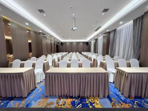 a conference room with rows of tables and white chairs at Fengqi Wutong Holiday Hotel - Changsha Wuyi Avenue Railway Station Metro Station Branch in Changsha