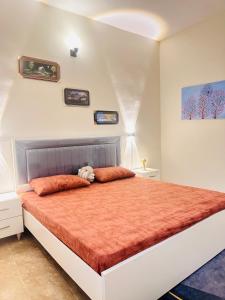 カラチにある2-BR Apartment-3 min airportのオレンジ色の枕が付いた大きなベッドのある寝室