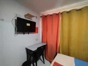 莎阿南KristaI Inn Hotel Shah Alam的客房设有桌子、电视和窗帘