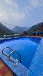 a large blue swimming pool with mountains in the background at Kaafirana Adventure Camps and Cottages in Shivpuri