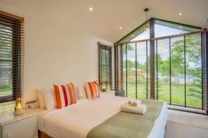 a bedroom with a large bed and large windows at The Hilltop Erawan in Si Sawat