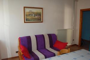 a living room with a purple couch with red pillows at Andron in Solkan