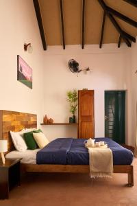 1 dormitorio con 1 cama grande con sábanas azules y almohadas verdes en Notu by Raho - Secluded Villa with Estate View, en Siddapur