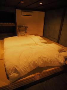 a large white bed in a dark room at 萩市の静かな港町の一棟貸切宿 泊まれるカフェ 龍さん家 -Japanese traditional house- in Hagi