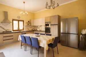 Una cocina con una mesa con sillas y un refrigerador. en Spacious Modern 3BR Oasis Villa with Private Pool, en Nadur