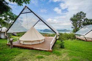 a white tent on a wooden deck in a field at The Hilltop Erawan in Si Sawat
