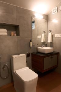 Un baño con un inodoro blanco y un lavabo. en Notu by Raho - Secluded Villa with Estate View, en Siddapur