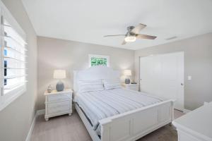 a white bedroom with a bed and a ceiling fan at Seashells #42 in Ybel