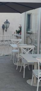 a row of white tables and chairs under an umbrella at Le Nouveau Grand Tour - Dimora del Commendatore in San Giorgio Morgeto