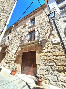 a stone building with a door and a balcony at Casa medieval Cal Moliner in Omells de Nagaya