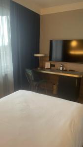 a bedroom with a bed and a desk with a television at Gresham Belson Hotel Brussels in Brussels