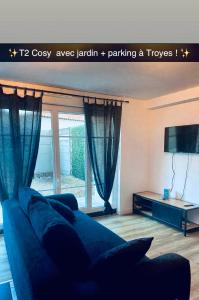 a living room with a blue couch and a tv at T2 Cosy avec jardin et parking gratuit à Troyes in Troyes