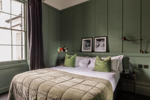 a bedroom with a large bed with green walls at The George in Cheltenham