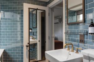 a blue tiled bathroom with a sink and a mirror at The George in Cheltenham +39 photos