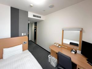 a room with a bed and a desk with a mirror at Comfort Hotel Gifu in Gifu