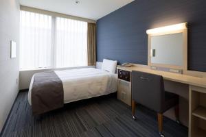 a hotel room with a bed and a desk with a mirror at Comfort Hotel Hakata in Fukuoka