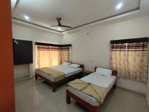a bedroom with two beds and a flat screen tv at Hiira Resort & homestay in Yercaud