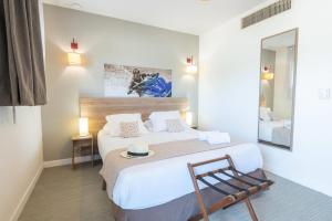 a bedroom with a bed with a chair and a mirror at Comfort Aparthotel Cannes Mandelieu in Mandelieu-la-Napoule +92 photos
