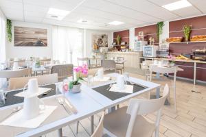 a restaurant with tables and chairs and a kitchen at Comfort Aparthotel Cannes Mandelieu in Mandelieu-la-Napoule
