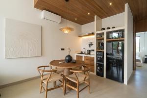 eine Küche und ein Esszimmer mit einem Holztisch und Stühlen in der Unterkunft Waves Bingin Luxury Apartments - Uluwatu by Yolla Hospitality in Bingin Beach