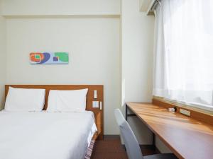a bedroom with a bed and a desk and a window at Comfort Inn Chiba Hamano in Chiba