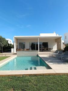 a swimming pool in front of a house at VILLA PETRA ARENAL D'en CASTELL in Es Mercadal