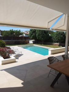 a swimming pool with an umbrella and a table and chairs at VILLA PETRA ARENAL D'en CASTELL in Es Mercadal