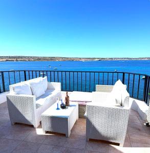 a patio with wicker chairs and a table and the ocean at Seafront apartment 2 bedrooms Terrace & Panoramic ocean views in Is-Sellum