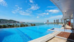 una piscina con vistas al agua y a los edificios en Vignette Collection Tiancheng Belmont Hotel Sanya by IHG, en Sanya