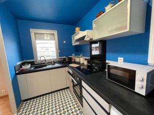 a kitchen with blue walls and a black counter top at Casino des fleurs in Vichy