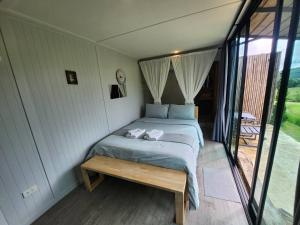 a bedroom with a bed and a wooden bench at the cabin hulk เขาใหญ่ in Ban Nong Song Hong