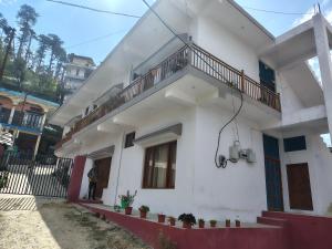 a white house with a balcony on the side at Nandin Guest House in Barkot