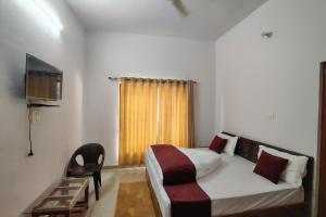 a bedroom with a bed and a chair and a television at Nandin Guest House in Barkot